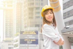 construção e manutenção pensam grande conceito, arquiteta feminina no capacete amarelo com fundo da cidade foto