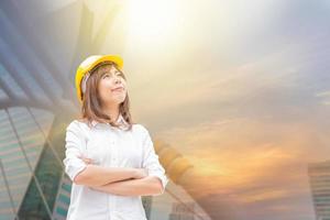 construção e manutenção pensam grande conceito, arquiteta feminina no capacete amarelo com fundo da cidade foto