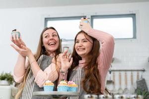 feliz mãe e filha orgulhosa mostrando bolo caseiro. tempo para a família desfrutar de padaria na cozinha juntos no fim de semana foto