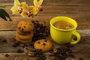 xícara de café, biscoitos e orquídea amarela foto