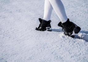 pés femininos em botas na neve foto