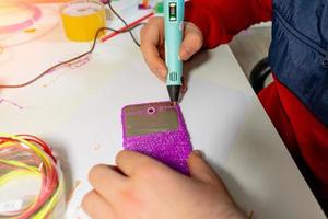 menino usando caneta 3d. criança feliz fazendo flor de plástico abs colorido. passatempo criativo em casa, tecnologia, lazer, conceito de educação. foto