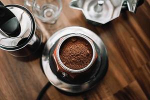 café moído finamente e cafeteira vintage moka pote na mesa de madeira em casa, foco seletivo. foto