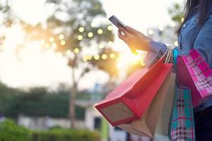 mulher usando smartphone com sacola de compras nas mãos