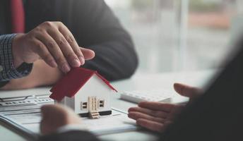 o corretor de imóveis está explicando o estilo da casa para os clientes que entram em contato para ver o projeto da casa e o contrato de compra. dentro de um escritório moderno foto