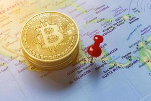 um alfinete vermelho está fixado no mapa-múndi de el salvador e há um bitcoin ao lado dele. foto