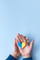coração de cores amarelo-azul da bandeira nacional da ucrânia nas mãos de uma criança, vista superior foto