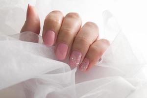 verniz rosa suave e brilhos nas unhas - manicure de revestimento de salão de verniz gel foto