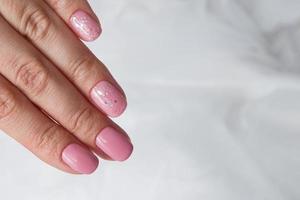 lindo verniz rosa suave e brilhos nas unhas - manicure de revestimento de salão de verniz gel foto