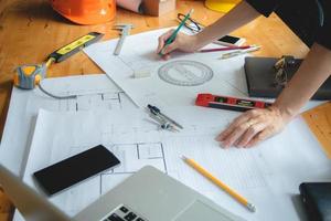 mãos de arquiteto ou engenheiro usando bússola de desenho com planta na mesa em office.team de arquitetos engenheiro discutindo e verificar documentos e conceito de workflow.construction de negócios. foto