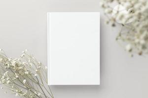 maquete de capa em branco de livro branco em um fundo bege com flor seca, postura plana, maquete foto