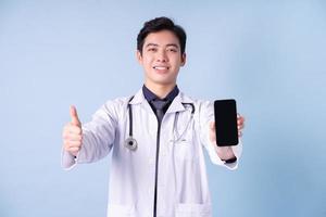 retrato de jovem médico masculino asiático sobre fundo azul foto