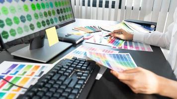 designer gráfico criativo escolhendo escala de cores para editar obras de arte enquanto trabalha no escritório.