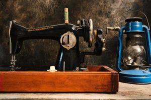 máquina de costura antiga, retrô, vintage e uma lâmpada de querosene em um fundo escuro de uma parede abstrata. foto