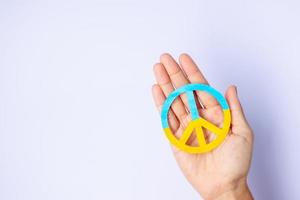 apoio à ucrânia na guerra com a rússia, mãos segurando o símbolo da paz com a bandeira da ucrânia. rezar, sem guerra, parar a guerra, ficar com a ucrânia e o desarmamento nuclear foto