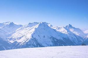 bela vista da cordilheira coberta de neve contra o céu azul claro foto
