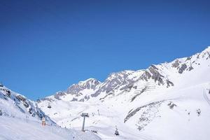 teleférico na montanha coberta de neve contra o céu azul claro foto