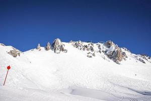 trilhas de esqui na montanha nevada contra o céu claro nos Alpes foto