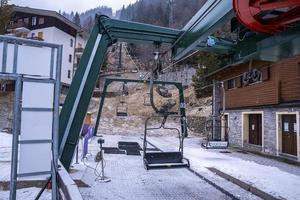 estação de teleféricos de cadeira vazia na estância de montanha de inverno com floresta de pinheiros foto