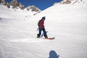 esquiador masculino esquiando na montanha nevada durante o dia ensolarado foto