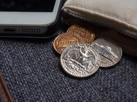 moedas de dólar americano colocadas fora da carteira com smartphone. foto
