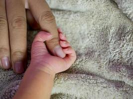 bebê recém-nascido segurando o dedo da mãe. conceito de cuidados com o bebê, sentindo-se seguro, amor dos pais. foco suave seletivo.