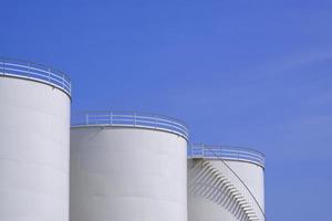 três tanques de combustível de armazenamento de óleo branco contra o fundo do céu azul, vista de baixo ângulo com espaço de cópia foto