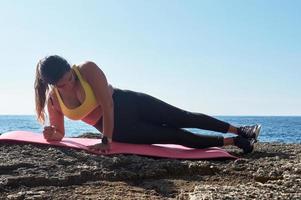 mulher latina, meia-idade, olhando para o aplicativo, relógio inteligente, descansando após a sessão de ginástica, vestindo blusa amarela, legging preta, haltere, queimando calorias, mantendo a forma, ao ar livre à beira-mar, foto