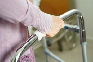 paciente com deficiência de mulher idosa asiática anda com andador no hospital de enfermagem, conceito médico. foto