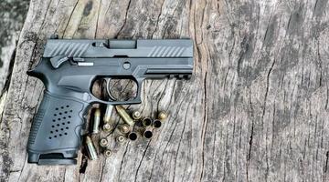 arma de pistola preta automática de 9 mm e balas na mesa de madeira. foto