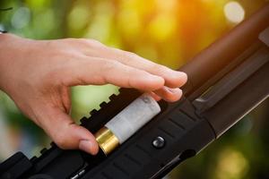 um atirador de espingarda está carregando um tiro no cano de uma espingarda longa. foto