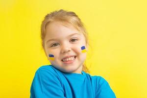 uma garota com uma bandeira ucraniana pintada de amarelo e azul nas bochechas foto