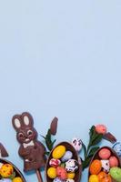 conceito de doces de caça de páscoa plana leiga com coelho de chocolate e ovos no espaço de cópia de fundo azul foto