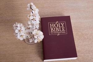 bíblia sagrada na vista de mesa com ramo de primavera florescendo foto