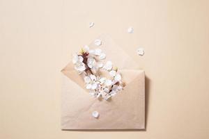 envelope kraft com um galho de primavera e flores brancas da primavera em um fundo bege foto