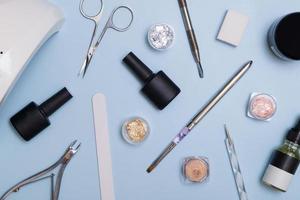 vista superior de ferramentas e materiais para manicure moderna e extensão de unhas. knolling em um fundo azul. ferramentas de manicure plana leiga foto