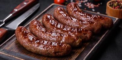 salsichas grelhadas com ingredientes em uma placa de corte em um fundo de pedra foto