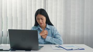 mulher asiática sentiu dor no peito enquanto estava sentado no trabalho. foto