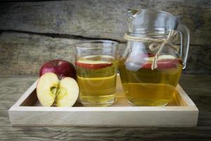 suco de maçã e maçãs em uma mesa de madeira foto