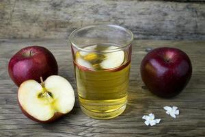 suco de maçã e maçãs em uma mesa de madeira foto