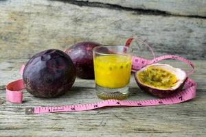 maracujás com copo de sucos de maracujá com fita métrica na mesa de madeira foto