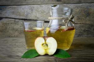 suco de maçã e maçãs em uma mesa de madeira foto