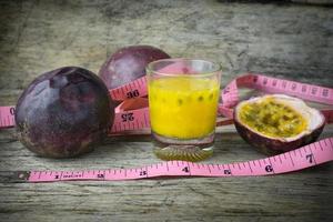 maracujás com copo de sucos de maracujá com fita métrica na mesa de madeira foto