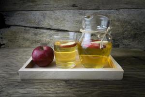 suco de maçã e maçãs em uma mesa de madeira foto