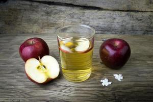 suco de maçã e maçãs em uma mesa de madeira foto