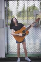 adolescente asiático tocando guitarra espanhola com emoção de felicidade foto