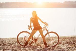 mulher de bicicleta perto da água