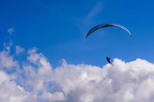 homem em um pára-quedas voando no céu claro foto