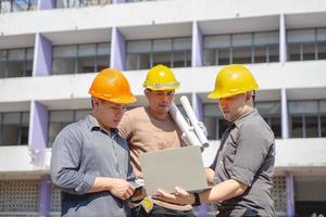 equipe de engenheiros e trabalhadores verificando o plano de construção de demolição e inspecionando no local. foto