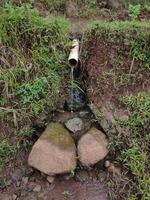 fotos do descarte de água simples do agricultor, durante o dia. feito usando materiais simples usando bambu. alguns usam um cachimbo.